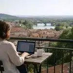 Personne travaillant sur ordinateur portable sur balcon, vue sur ville