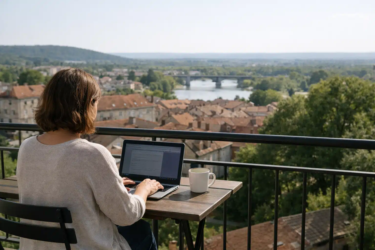 Personne travaillant sur ordinateur portable sur balcon, vue sur ville