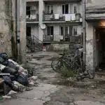 Cour d'immeuble délabrée avec poubelles et vélos